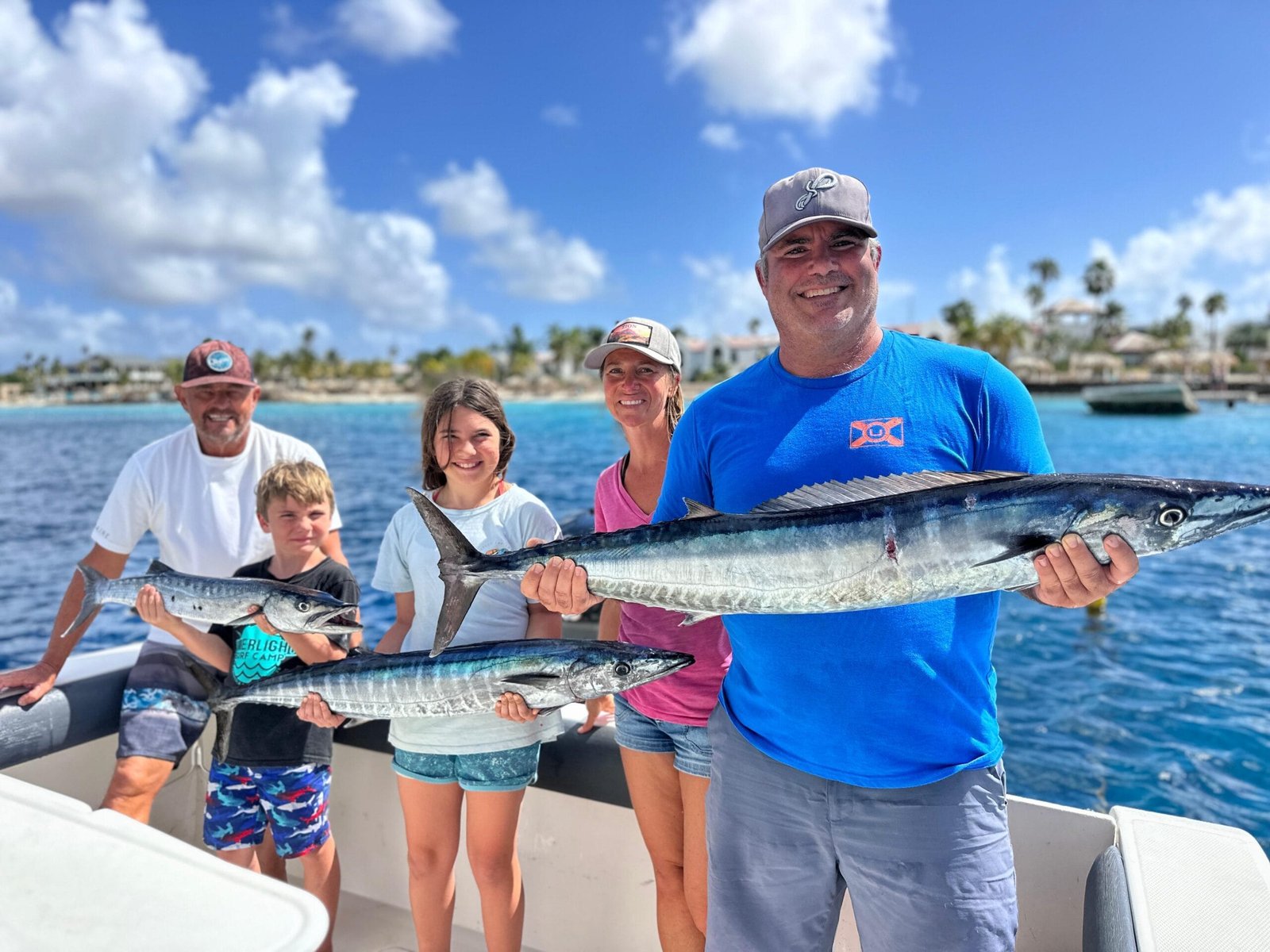 Mom, dad, daughter and son each holding a large fish and standing in boat with Captain Hagen in the background.